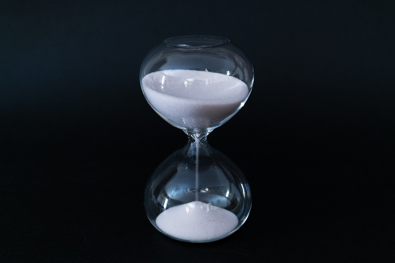 An hourglass mid-pour against black